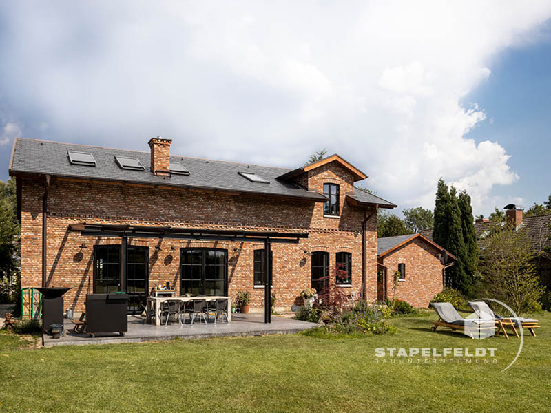 Haus bauen Bauunternehmen Hamburg Tatenberg Neubau Neubauvorhaben Hausbau Wohnhaus Industrial Style Einfamilienhaus Bruchstein Emden Granitsockel Verblendmauerwerk Rohbau Zierverbände Fassadenverblendung Stapelfeldt Bauunternehmung