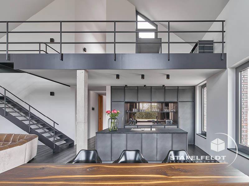 Offener Wohnbereich mit moderner Küche, Galerie und Treppe im Architektenhaus-Neubau in Hamburg-Curslack (Vier- und Marschlande) – Stapelfeldt Bauunternehmung.