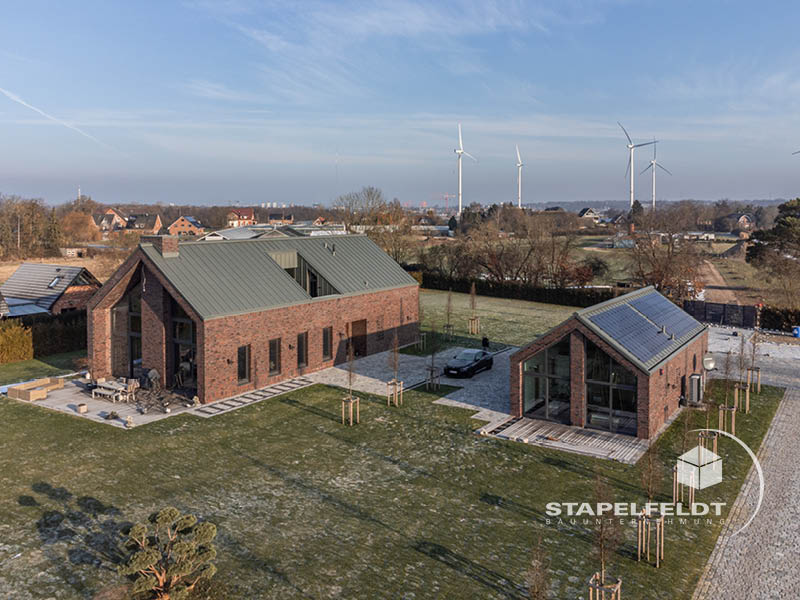 Luftaufnahme des Neubau-Ensembles in Hamburg-Curslack mit Klinkerbauten und Metall­dächern