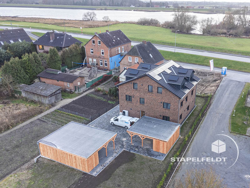 Luftbild: Neubau Mehrfamilienhaus in Hamburg-Kirchwerder nahe dem Elbdeich; Außenanlagen mit Carports in den Vier- und Marschlanden.