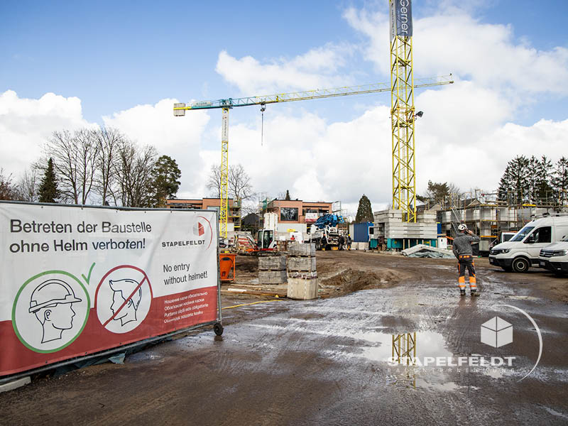 Baustellenschild zur Helmpflicht vor dem Wohnquartier Reiherstieg in Lüneburg mit Kränen im Hintergrund