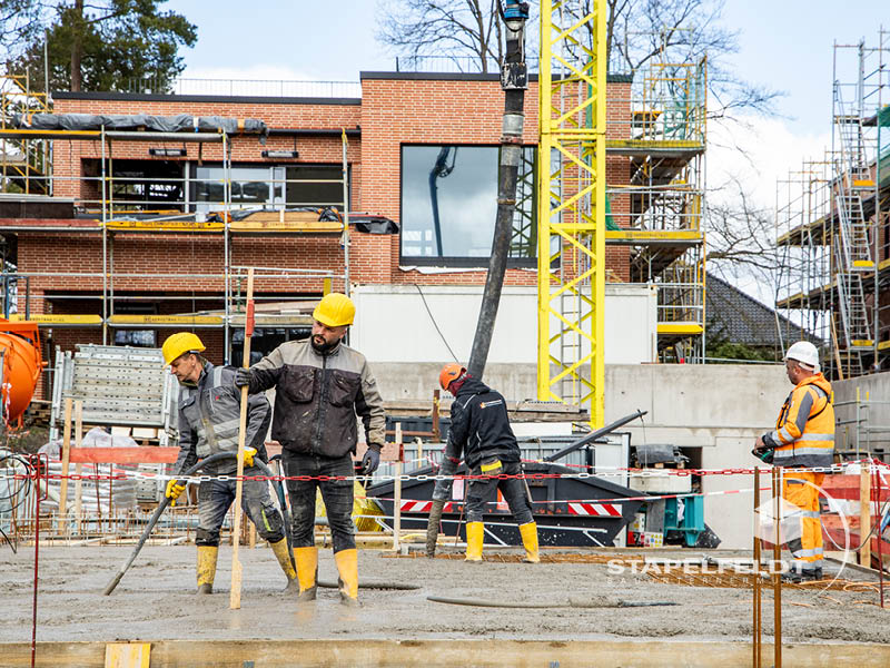 Bauarbeiter glätten frischen Beton vor Klinkerrohbau und Gerüst im Wohnquartier Reiherstieg in Lüneburg