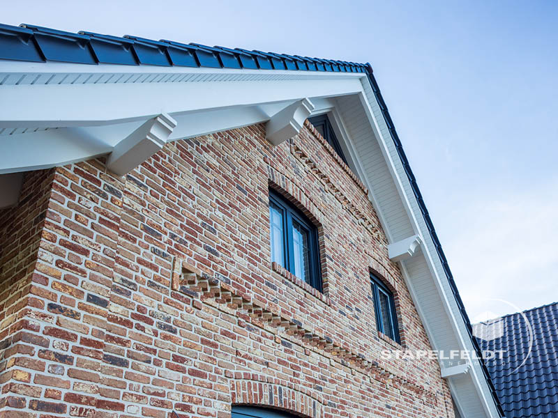 Giebel eines Klinker-Einfamilienhauses mit Rundbogenfenstern und weißen Sparren | Bauunternehmen exklusives Einfamilienhaus Landkreis Lüneburg