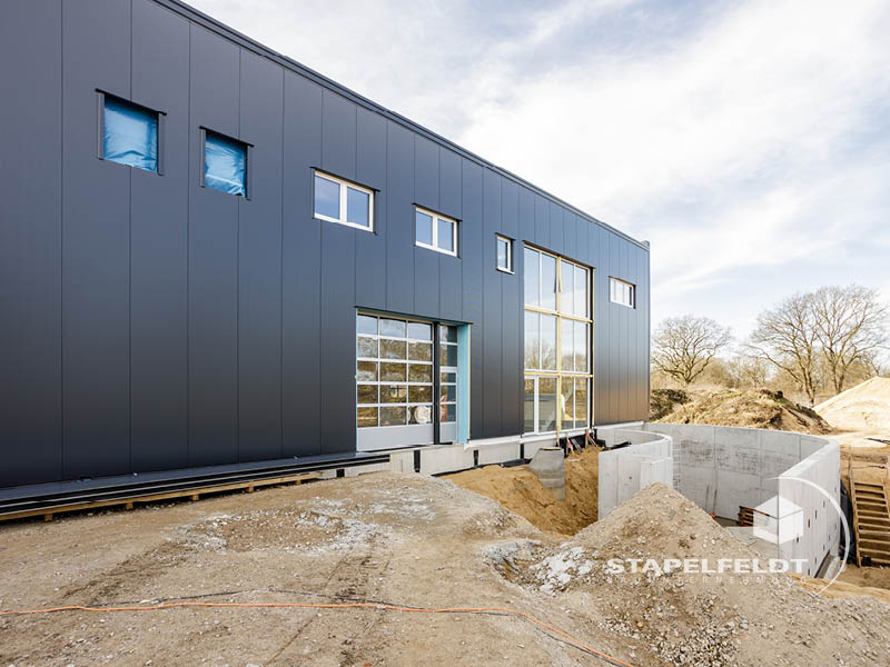 Seitenansicht der Hallenfassade mit Tor und Glasfront, Autowerkstatt-Halle Norderstedt.